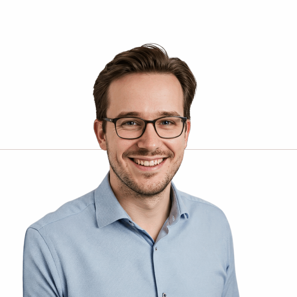 Freundliches Porträt eines jungen Mannes namens Michael mit Brille, Bart und einem hellblauen Hemd, der lächelnd in die Kamera blickt.